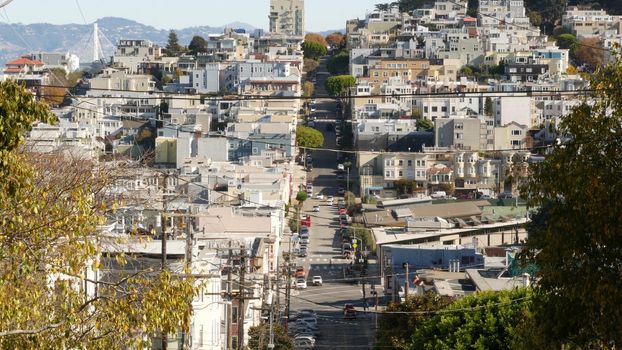 Iconic hilly street and crossroads in San Francisco, Northern California, USA. Steep downhill road and pedestrian walkway. Downtown real estate, victorian townhouses abd other residential buildings.