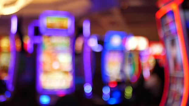 Defocused slot machines glow in casino on fabulous Las Vegas Strip, USA. Blurred gambling jackpot slots in hotel near Fremont street. Illuminated neon fruit machine for risk money playing and betting.