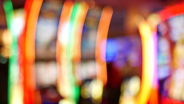 Defocused slot machines glow in casino on fabulous Las Vegas Strip, USA. Blurred gambling jackpot slots in hotel near Fremont street. Illuminated neon fruit machine for risk money playing and betting.