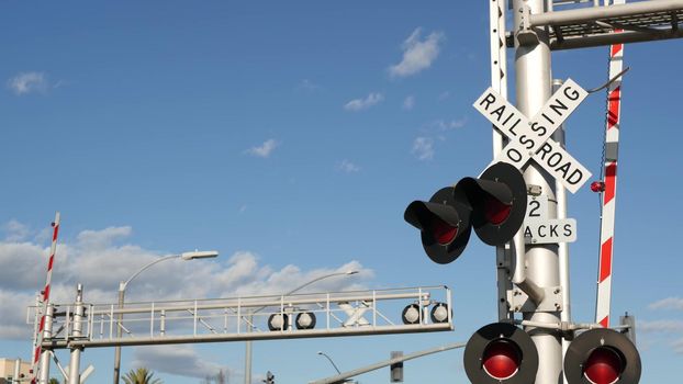 Level crossing warning signal in USA. Crossbuck notice and red traffic light on rail road intersection in California. Railway transportation safety symbol. Caution sign about hazard and train track.