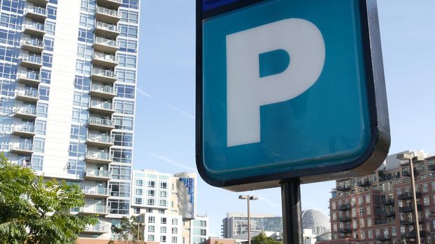 Parking lot sign as symbol of traffic difficulties and transportation issues in busy urban areas of USA. Public paid parking zone in downtown of San Diego, California. Limited space for cars in city.