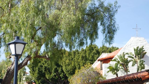 Mexican colonial style suburban, hispanic house exterior, green lush garden, San Diego, California USA. Mediterranean terracotta ceramic clay tile on roof. Rustic spanish tiled rooftop. Rural details.