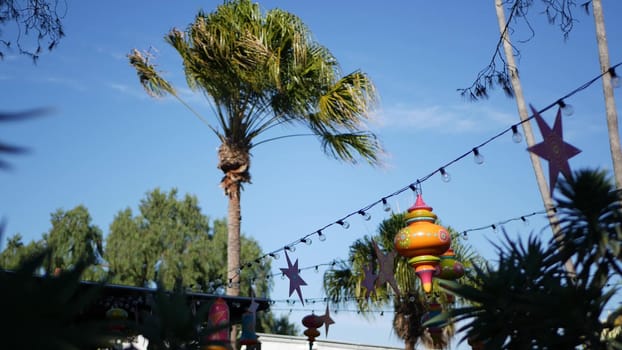 Festive mexican colourful decoration for holiday. Festival authentic decor in garden, details of garland with light bulbs in San Diego, California USA. Festal multi colored traditional celebration.