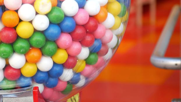 Colorful gumballs in classic vending machine, USA. Multi colored buble gums, coin operated retro dispenser. Chewing gum candies as symbol of childhood and summertime. Mixed sweets in vintage automate.