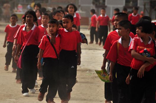 NAKHONSITHAMMARAT, THAILAND - JUNE 7, 2014: Group of pupils of oriental province, Group of many children walking on street of oriental province after school