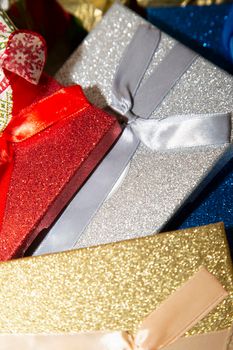 Red, silver, blue, and gold Christmas packages next to a red and green burlap ribbon
