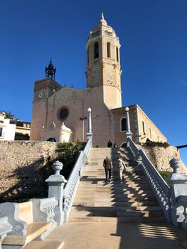 couple walking towards the Church of Sant Bartomeu & Santa Tecla in Sitges, Spain