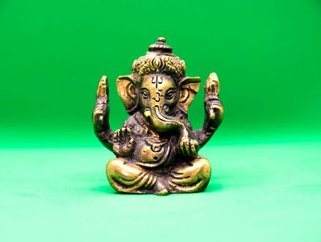 Statuette of an elephant Ganesha made of brass on a green background. Ganesha also known as Ganapati and Vinayaka , is one of the best-known and most worshipped deities in the Hindu pantheon.