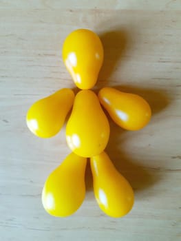 On the kitchen table there is a funny figure of a man made of ripe yellow tomatoes.