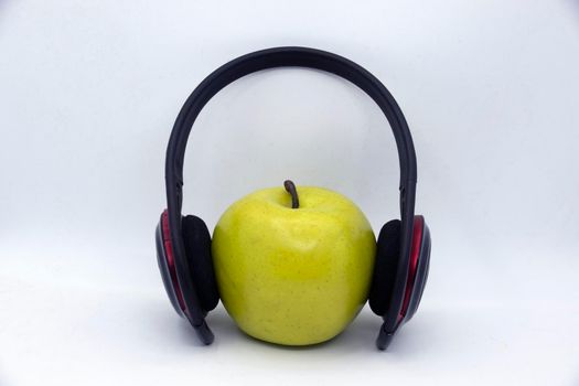 Green apple in headphones on white background.