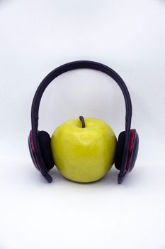 Green apple in headphones on white background.