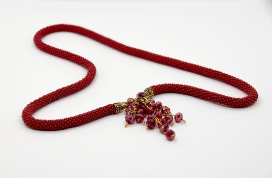 A red beaded necklace rests on a white surface.