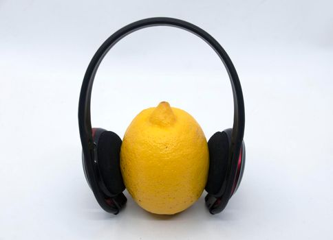 Yellow lemon in headphones on a white background.