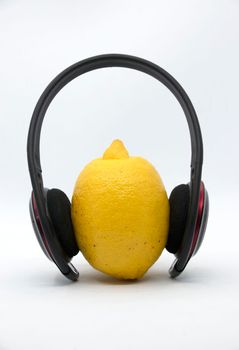 Yellow lemon in headphones on a white background.