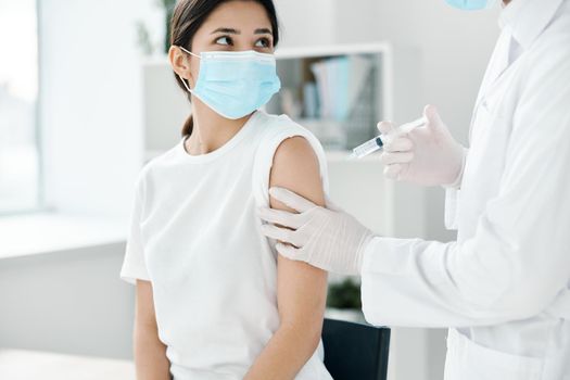 doctor in protective gloves holds a woman's hand and injects a vaccine against covid-19 coronavirus. High quality photo