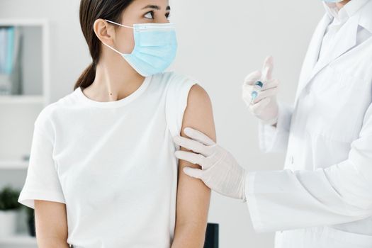 male doctor giving vaccination injection in the shoulder of a woman in a medical mask. High quality photo