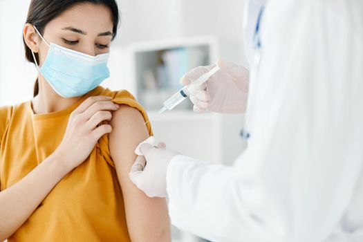 patient in a medical mask looks at the doctor with a syringe in hand vaccination. High quality photo