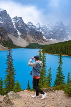 The beautiful Lake moraine at sunset, Beautiful turquoise waters of the Moraine lake with snow-covered rocky mountains in Banff National Park of Canada Lake Louise, men looking out over the lake