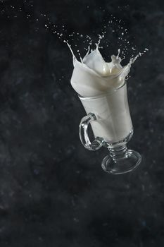 Splash of milk from the glass on a gray background. levitation.