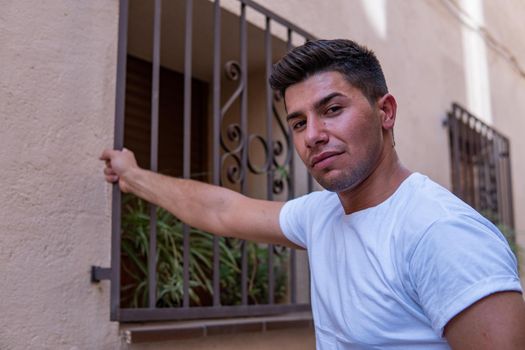 Man holding a fence in a white shirt