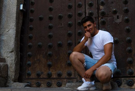 Man with a white T-shirt and a brown door in the background modeling