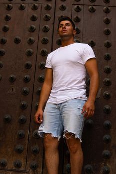 Man with a white T-shirt and a brown door in the background modeling