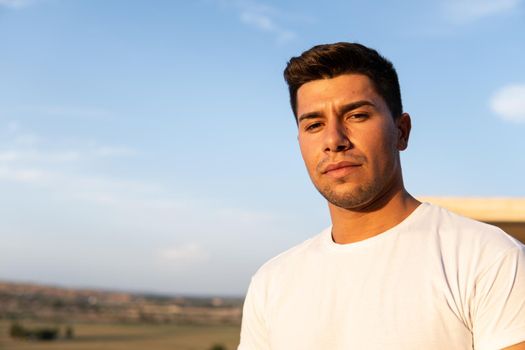 Boy with white T-shirt and brown hair with sky in the background