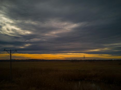 Dark landscape of sunset over yellow fields from train