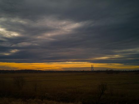 Dark landscape of sunset over yellow fields from train