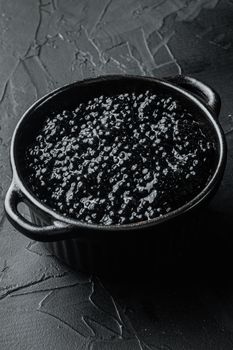 Black bowl of black caviar, on black background