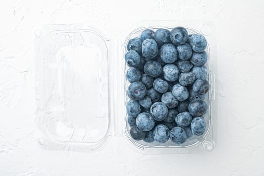Blueberries, in clear plastic tray, on white background, top view flat lay
