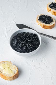 Black caviar served on baguettes, on white background