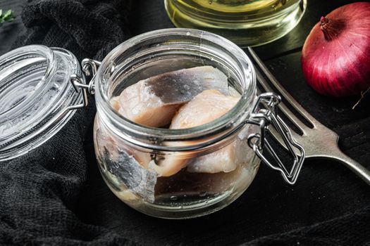 Herring pieces drenched in oil, on black wooden table background