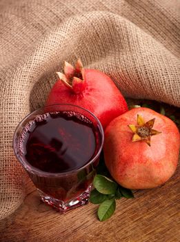 Garnet juice in a glass and pomegranate on wooden boards