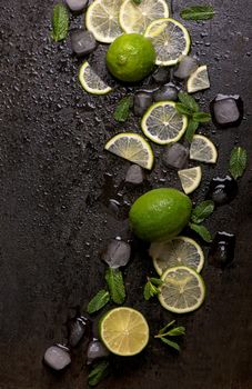 Fresh mint, lime and ice on a black background. Ingredient for mahito. Top view