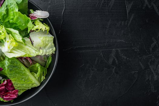 Fresh leaves of different lettuce salads, on black background, top view flat lay with copy space for text