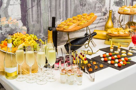 Delicious desserts on the Banquet table. Fruit, cocktails, wine, ice cream with jam, cookies with cream.