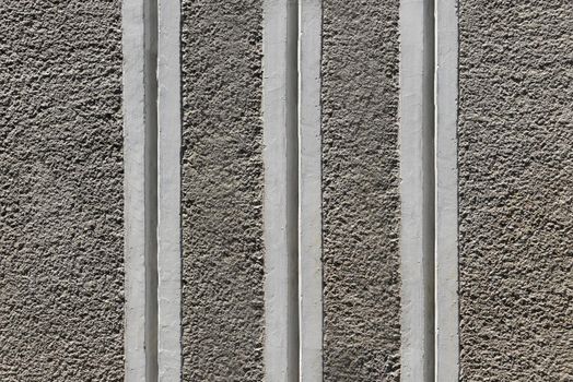 Gray rough concrete wall with striped vertical stripes close-up.Texture or background