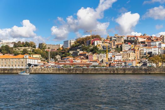 Porto, Portugal - October 23, 2020: View of the buildings with typical architecture and boats of tourist areas on the banks of the Douro river on an autumn day