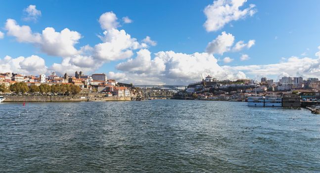 Porto, Portugal - October 23, 2020: View of the buildings with typical architecture and boats of tourist areas on the banks of the Douro river on an autumn day