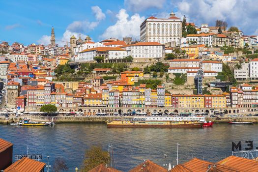 Porto, Portugal - October 23, 2020: View of the buildings with typical architecture and boats of tourist areas on the banks of the Douro river on an autumn day