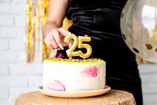 Birthday party. Beautiful brunette woman in black party dress holding ballooncelebrating her birthday cutting the cake