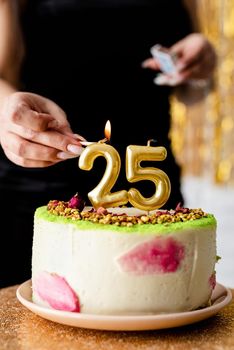 Birthday party. Caucasian woman in black party dress lighting candles on birthday cake