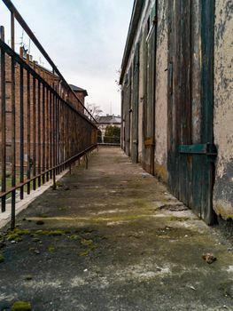 Long concrete balcony between metal railing and old wooden doors