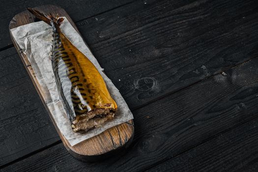 Smoked mackerel fish, on black wooden table background with copy space for text