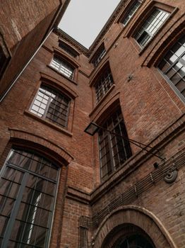 Upward view to high building red brick wall with big windows