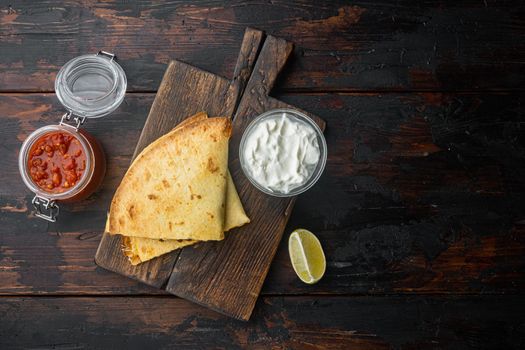 Grilled quesadillas or tortillas with cheese mix, on old dark wooden table background, top view flat lay with copy space for text