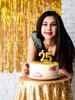 Birthday party. Beautiful woman in black party dress celebrating her birthday ready to blow candles on the cake