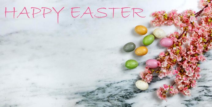 Happy Easter concept with springtime cherry blossoms and colorful eggs on stone background plus text message