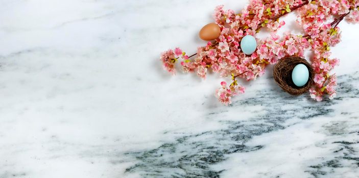 Happy Easter concept with springtime cherry blossoms and small bird nest with one egg inside on stone background in flat lay format 